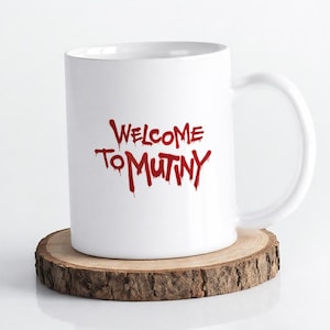 May include: A white ceramic mug with a handle on the right side. The front of the mug features the text "WELCOME TO MUTINY" printed in a bold, red, dripping font that resembles liquid paint or blood, creating a stark contrast against the white surface.