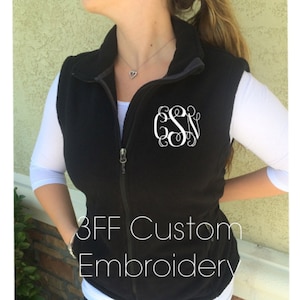 May include: Black fleece vest with a white monogram "CSN" embroidered on the front. The vest has a zip fastening and a grey collar. The text "3FF Custom Embroidery" is printed on the bottom of the vest.