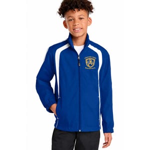 May include: A blue zip-up jacket with white detailing on the shoulders and sides. The jacket, worn by a person, has a school logo on the chest. It features a stand-up collar and pockets. The jacket is a school uniform.