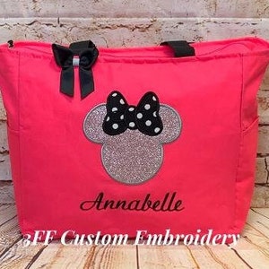 May include: A bright pink tote bag with black straps and a black and white polka dot Minnie Mouse design. The bag is personalized with the name "Annabelle" and the text "3FF Custom Embroidery".