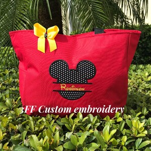 May include: Red canvas tote bag with a black and white polka dot Mickey Mouse head design and the name "Robinson" embroidered in black. The bag has a yellow bow on the top and the text "3FF Custom embroidery" is printed on the bottom.