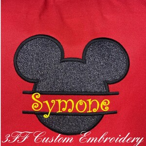 Puede incluir: Bolsa de tela roja con una cabeza de Mickey Mouse negra y plateada con purpurina, con el nombre "Simone" bordado en amarillo en la parte inferior. El texto "3FF Custom Embroidery" est&aacute; bordado en blanco en la parte inferior de la bolsa.