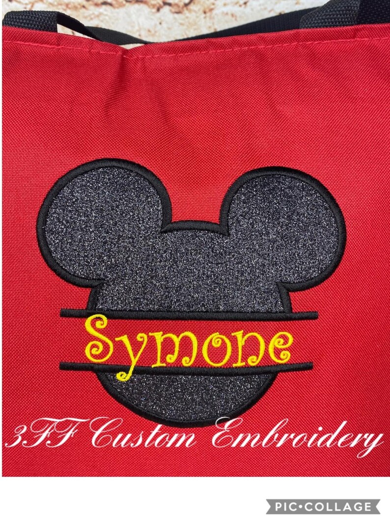 Puede incluir: Bolsa de tela roja con una cabeza de Mickey Mouse negra y plateada con purpurina, con el nombre "Simone" bordado en amarillo en la parte inferior. El texto "3FF Custom Embroidery" est&aacute; bordado en blanco en la parte inferior de la bolsa.