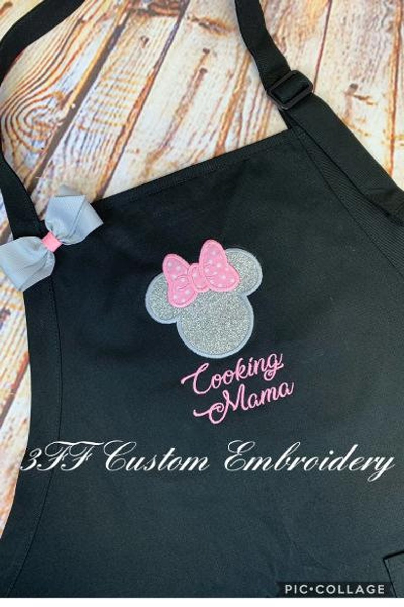 May include: Black apron with a silver and pink embroidered Minnie Mouse head and the text "Cooking Mama". The apron also has the text "3.F Custom Embroidery" at the bottom.