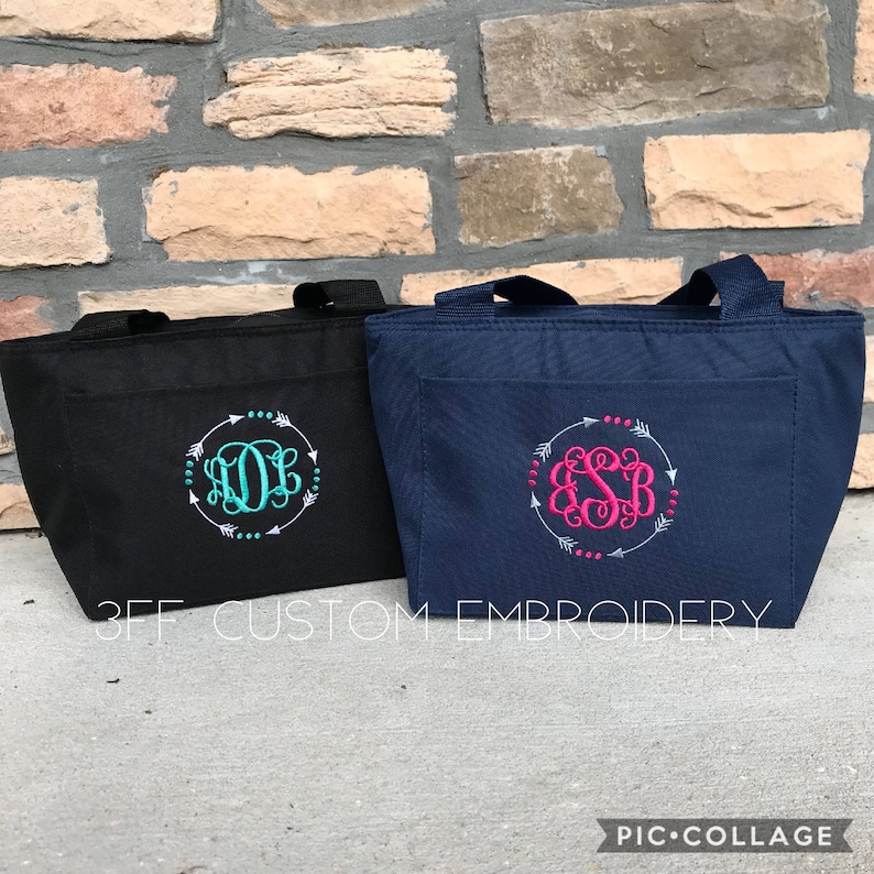 Puede incluir: Dos bolsas de almuerzo aisladas con monogramas personalizados. La bolsa de la izquierda es negra con un monograma turquesa y la bolsa de la derecha es azul marino con un monograma rosa. Ambas bolsas tienen un dise&ntilde;o de flechas blancas alrededor del monograma.