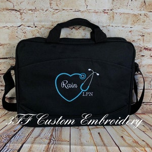 May include: Black canvas messenger bag with a blue embroidered heart and stethoscope. The heart has the name "Rain" and the text "LPN" embroidered inside.