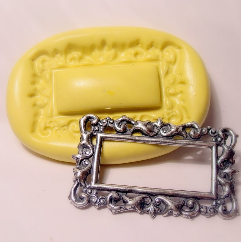 May include: A yellow silicone mould for making a decorative frame. The mould is shaped like a rectangle with a detailed, ornate design. A silver metal frame is shown next to the mould.