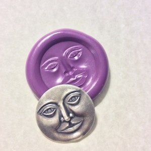 May include: A purple silicone mold of a face with a smiling expression. A silver metal casting of the face is shown next to the mold.