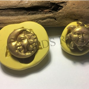 Peut inclure: Deux moules en silicone jaunes avec des motifs célestes dorés. L'un des moules représente un croissant de lune avec un visage, et l'autre un soleil souriant. Les moules sont probablement destinés à l'artisanat ou à la fabrication de bijoux.