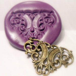 May include: A purple silicone mold with a detailed ornate design, and a matching bronze metal pendant with a similar design.