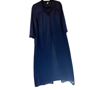 May include: A long, navy blue robe with a button-down front and three-quarter sleeves. The robe has a collar and delicate embroidered detailing around the neckline. The fabric appears lightweight and flowing, suitable for lounging.