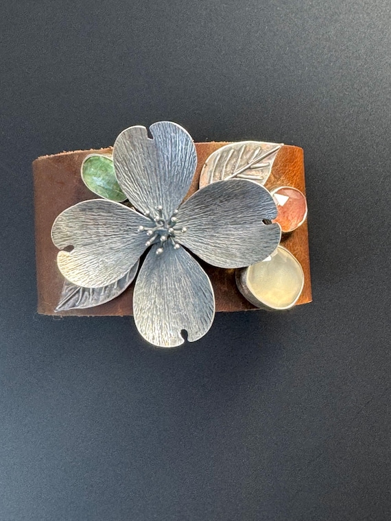Hand forged dogwood blossom on leather cuff with gemstones