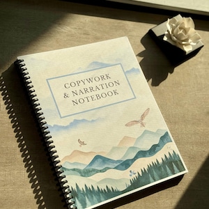 May include: Spiral-bound notebook with the text "COPYWORK & NARRATION NOTEBOOK" in a blue frame. The cover features a watercolor landscape of mountains, trees, and flying birds. The notebook is on a wooden surface.
