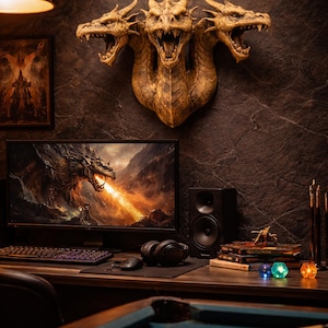 May include: A three-headed dragon wall sculpture in gold tones is mounted on a dark textured wall. A computer monitor displays a dragon breathing fire. A desk with a keyboard, mouse, and headphones is in front of the monitor. A pool table is in the foreground.