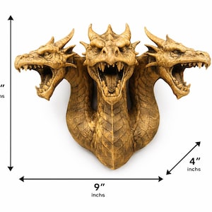 May include: A detailed, golden-colored three-headed dragon sculpture. The sculpture is 9 inches tall and 9 inches wide, with a depth of 4 inches. The dragon has an open mouth with visible teeth and is mounted on a white background.