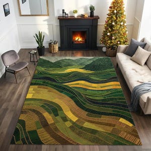 May include: A large area rug with a landscape design. The rug features rolling hills in shades of green, yellow, and brown, with a dark blue accent. The design is detailed with gold-colored lines. The rug is placed in a living room setting.