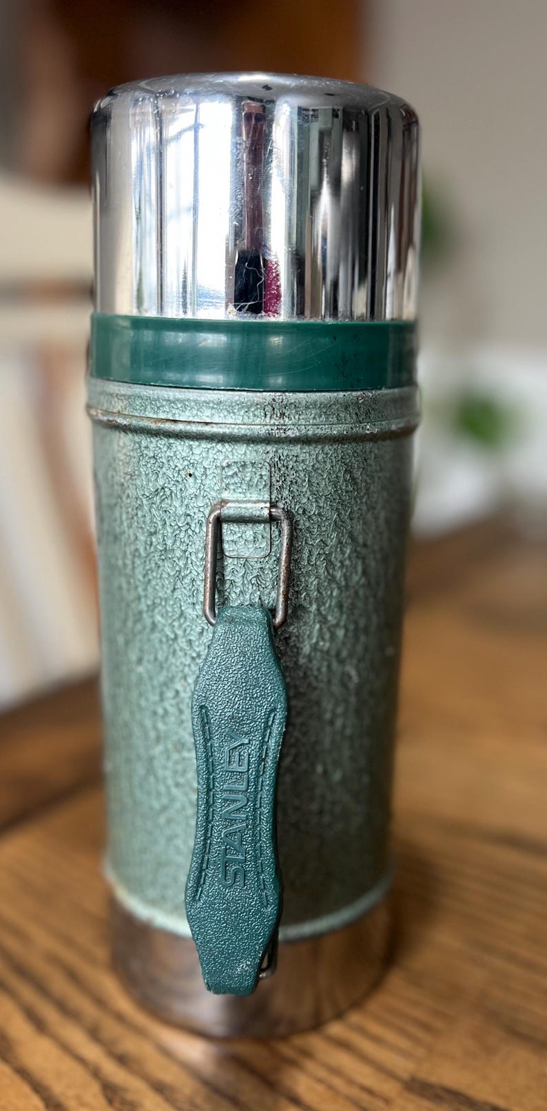 Puede incluir: Termo Stanley vintage en acabado verde texturizado con tapa plateada brillante. El termo tiene un asa de cuero verde con el logotipo de Stanley. Un art&iacute;culo cl&aacute;sico para mantener las bebidas calientes o fr&iacute;as.