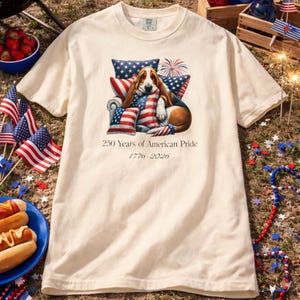 America 250 dog shirt cream ivory color styled outdoors with hot dogs flags and summer Independence Day decor.