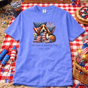 America 250 patriotic dog shirt in flo blue Comfort Colors tee with picnic setup fireworks basket and summer celebration theme.
