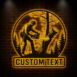 Puede incluir: Un letrero de neón que representa a un leñador cortando un árbol con una motosierra, dentro de un marco circular. El diseño incluye siluetas de árboles y el texto "CUSTOM TEXT" en un recuadro rectangular, todo en un cálido resplandor amarillo sobre un fondo de ladrillo.