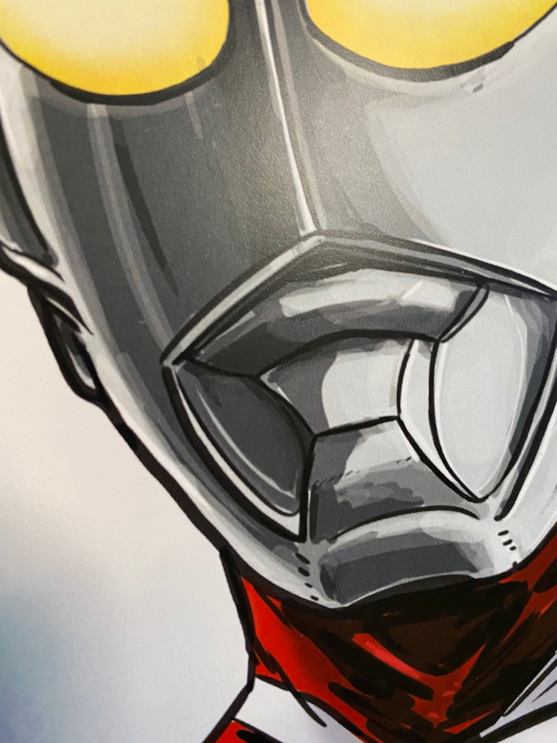 May include: Close-up of a silver and gray superhero mask with yellow eyes. The mask has a red and black scarf around the neck.