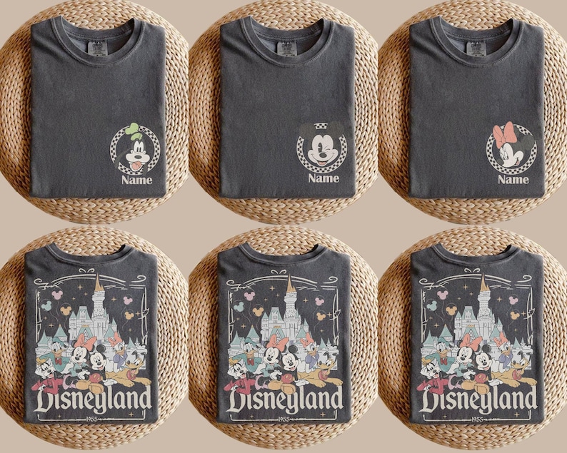 May include: Six dark gray t-shirts. The top row features Goofy, Mickey Mouse, and Minnie Mouse designs with the word "Name" below. The bottom row displays a Disneyland graphic with various cartoon characters and the text "Disneyland 1955".