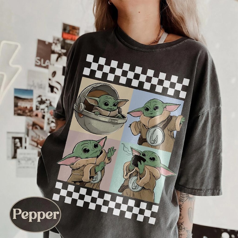 Pode incluir: Camiseta cinza escuro com um gr&aacute;fico de quatro pain&eacute;is de Grogu de The Mandalorian. Cada painel mostra Grogu em poses diferentes, com uma borda de padr&atilde;o de xadrez. A camiseta tem um visual vintage.