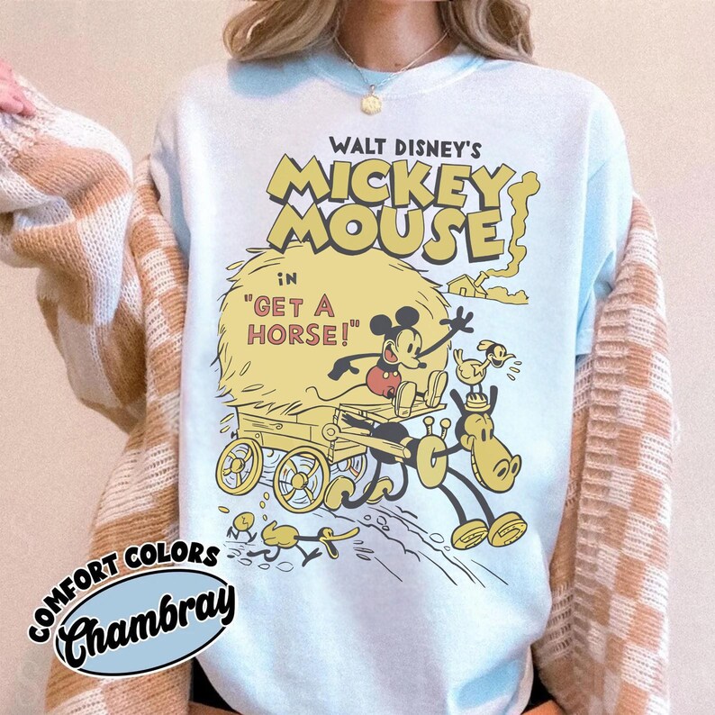 May include: Light blue sweatshirt featuring a vintage Mickey Mouse graphic from "Get a Horse!". The design includes Mickey Mouse, a horse, and a hay cart in yellow and black. The text "WALT DISNEY'S MICKEY MOUSE" is above the graphic.