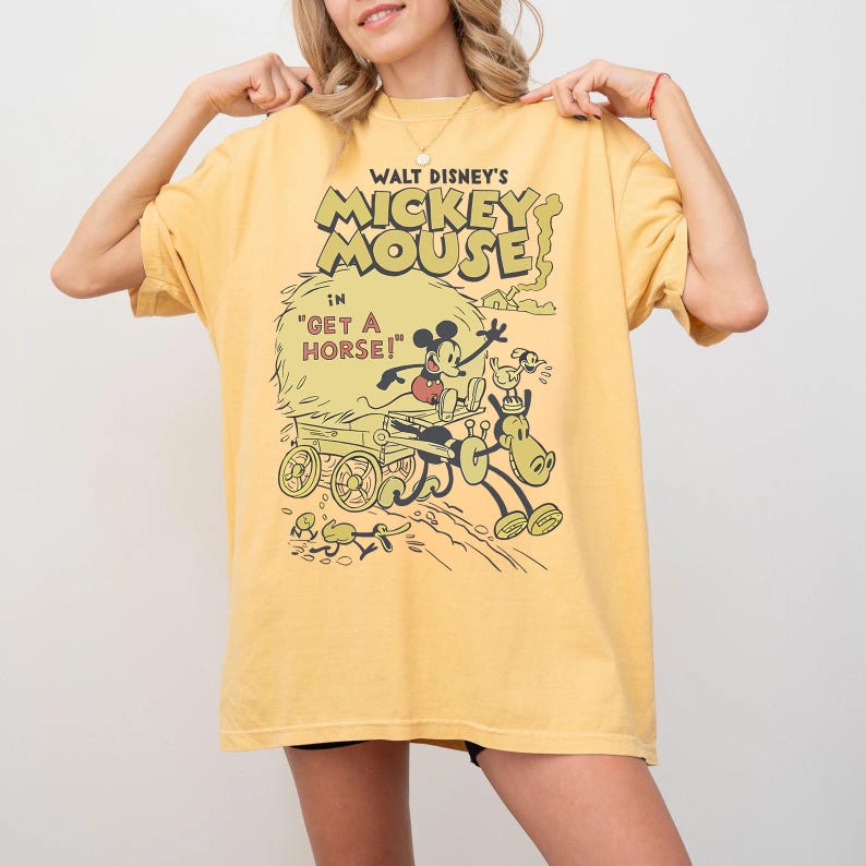 May include: Yellow t-shirt featuring a vintage Walt Disney's Mickey Mouse graphic. The design includes Mickey Mouse, a horse, and the text "Get a Horse!". The shirt has a classic, slightly faded look.