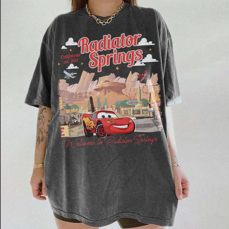 May include: A white ceramic mug with a black handle and the text "But First, Coffee" in a black, handwritten-style font. The mug is on a white surface.