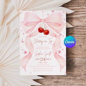 May include: A baby shower invitation with a watercolor design. The invitation features a pink bow, ribbons, and cherries. The text reads "She's the Cherry on Top" and includes event details. The background is a wooden surface.