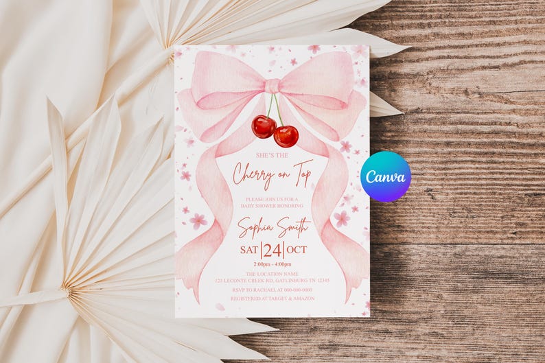 May include: A baby shower invitation with a watercolor design. The invitation features a pink bow, ribbons, and cherries. The text reads "She's the Cherry on Top" and includes event details. The background is a wooden surface.