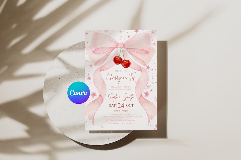 May include: A baby shower invitation with a watercolor design. The invitation features a pink bow, ribbons, and cherries. The text reads "She's the Cherry on Top" with event details and the Canva logo.