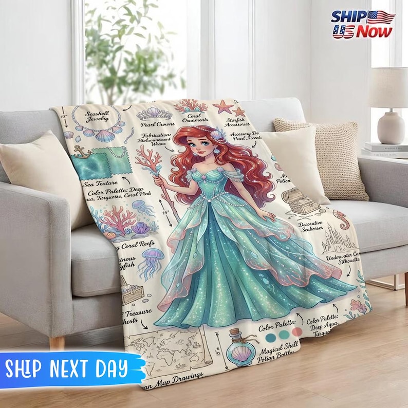 May include: A beige throw blanket featuring a detailed illustration of a mermaid in a teal gown, holding a staff. The blanket includes drawings of seashells, coral, and a map. The blanket is approximately 57 inches long.