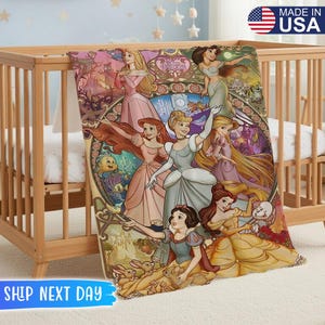 May include: A colorful blanket featuring various Disney princesses in a stained-glass style design. The blanket is draped over a wooden crib. The words "Made in USA" are visible in the upper right corner.