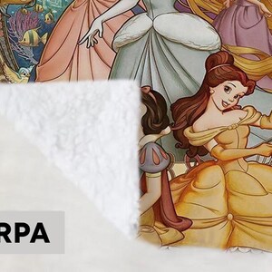 May include: Sherpa blanket featuring a colorful illustration of Disney princesses. Belle is in the foreground, wearing a yellow gown and holding a purse. Other princesses are also depicted. The blanket has a soft, white texture.