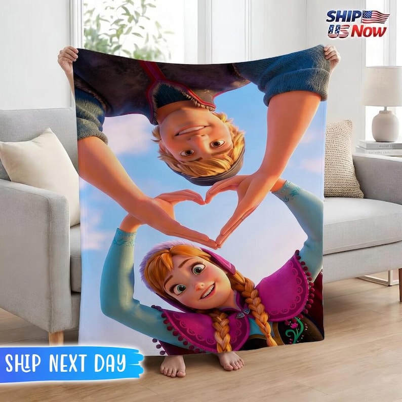 May include: A large, rectangular blanket featuring a colorful image of two animated characters forming a heart shape with their hands. The blanket has a blue sky background and the words "SHIP NEXT DAY".