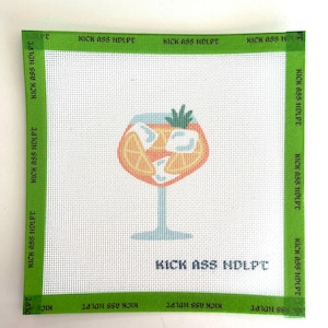May include: Square needlepoint canvas with a green border and the text "KICK ASS NDLPT". The canvas features a cartoon cocktail with ice cubes and a garnish. The background is white.
