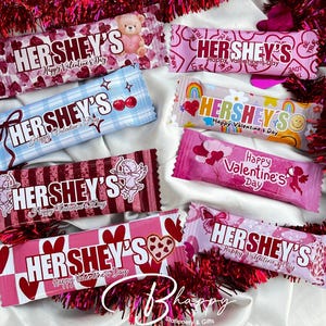 May include: Assortment of Hershey's chocolate bars with Valentine's Day packaging. Designs include hearts, teddy bears, cherubs, and the text "Happy Valentine's Day". The bars are in various colors, including pink, red, and blue.