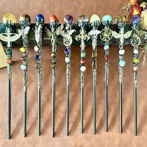 May include: Ten decorative hair sticks with intricate metalwork and gemstone details. Each stick has a different coloured gemstone and decorative charms, such as angels and crosses. The hair sticks are displayed against a brown background.