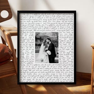 May include: A framed vertical print featuring a black and white photograph of a bride and groom in the center, surrounded by repeating lines of black cursive text on a white background, all enclosed within a simple black rectangular frame.