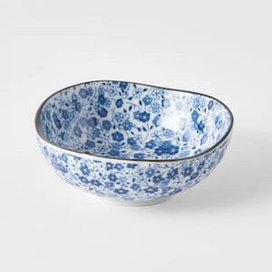 K&ouml;nnte beinhalten: Eine kleine, runde Keramikschale mit einem unregelm&auml;&szlig;igen, organischen Rand. Die Schale hat eine wei&szlig;e Basis, die mit einem dichten, sich wiederholenden Muster aus kleinen blauen Blumen und zartem Blattwerk verziert ist.