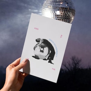 May include: A white card with the text "KISS THE DISCO OCCASIONALLY ALL" and a black and white image of a person leaning on a disco ball. A large disco ball is in the background.