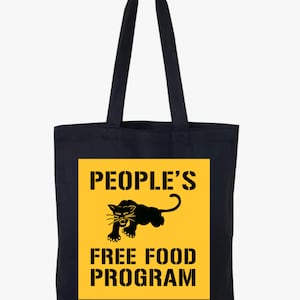May include: Black tote bag with a yellow square featuring a black panther illustration and the text "PEOPLE'S FREE FOOD PROGRAM". The bag has long handles for carrying and is made of a dark fabric.