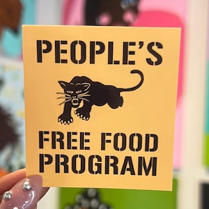 May include: A yellow sticker with black text and a black panther illustration. The text reads "PEOPLE'S FREE FOOD PROGRAM" in a bold, stencil-like font. The panther is depicted in a dynamic pose.