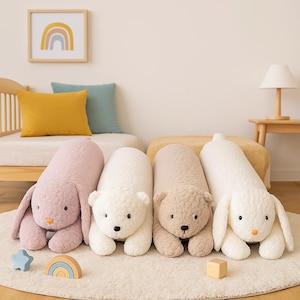 May include: Four plush animal pillows: a pink bunny, a white polar bear, a tan bear, and a white bunny. The pillows are lying on a white rug. A wooden rainbow and star are in the foreground.