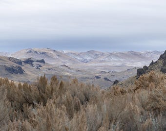 Artemisa enmarcando un valle bajo colinas nevadas. Impresión fotográfica.