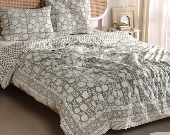 May include: A bed with a green and white floral patterned quilt and two matching pillowcases. The bedding has a detailed floral design and a striped border. The headboard is made of woven rattan.