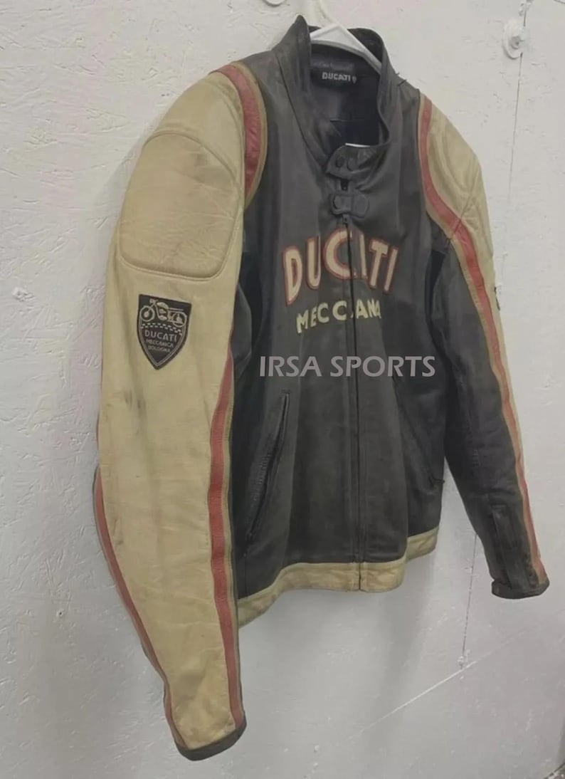 May include: A vintage Ducati motorcycle jacket in black and cream with red stripes. The jacket features the Ducati logo and the text "MECCAN" on the front. A patch with the Ducati logo is on the left sleeve. The text "IRSA SPORTS" is also visible.