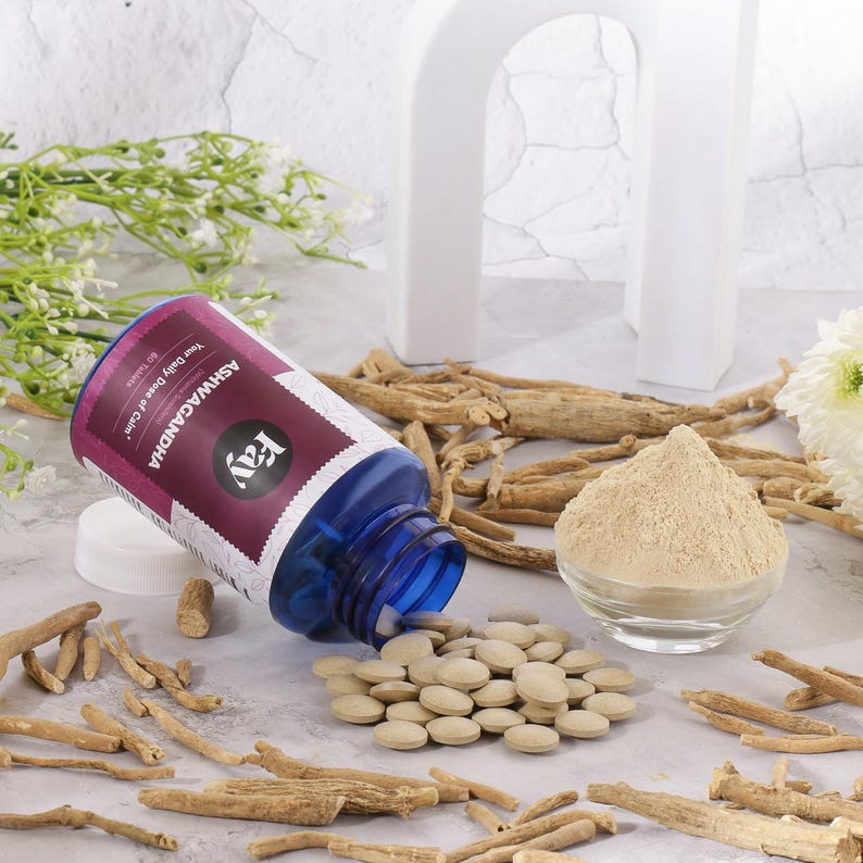May include: A blue bottle of Ashwagandha tablets with a purple and white label, alongside a pile of tablets, a small bowl of powder, and dried roots. The label reads "Your Daily Dose of Calm."